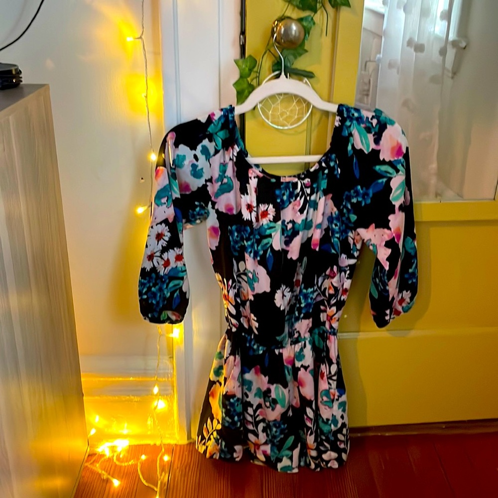 Summery black romper with pink and blue tropical flowers. Flowy sleeves.